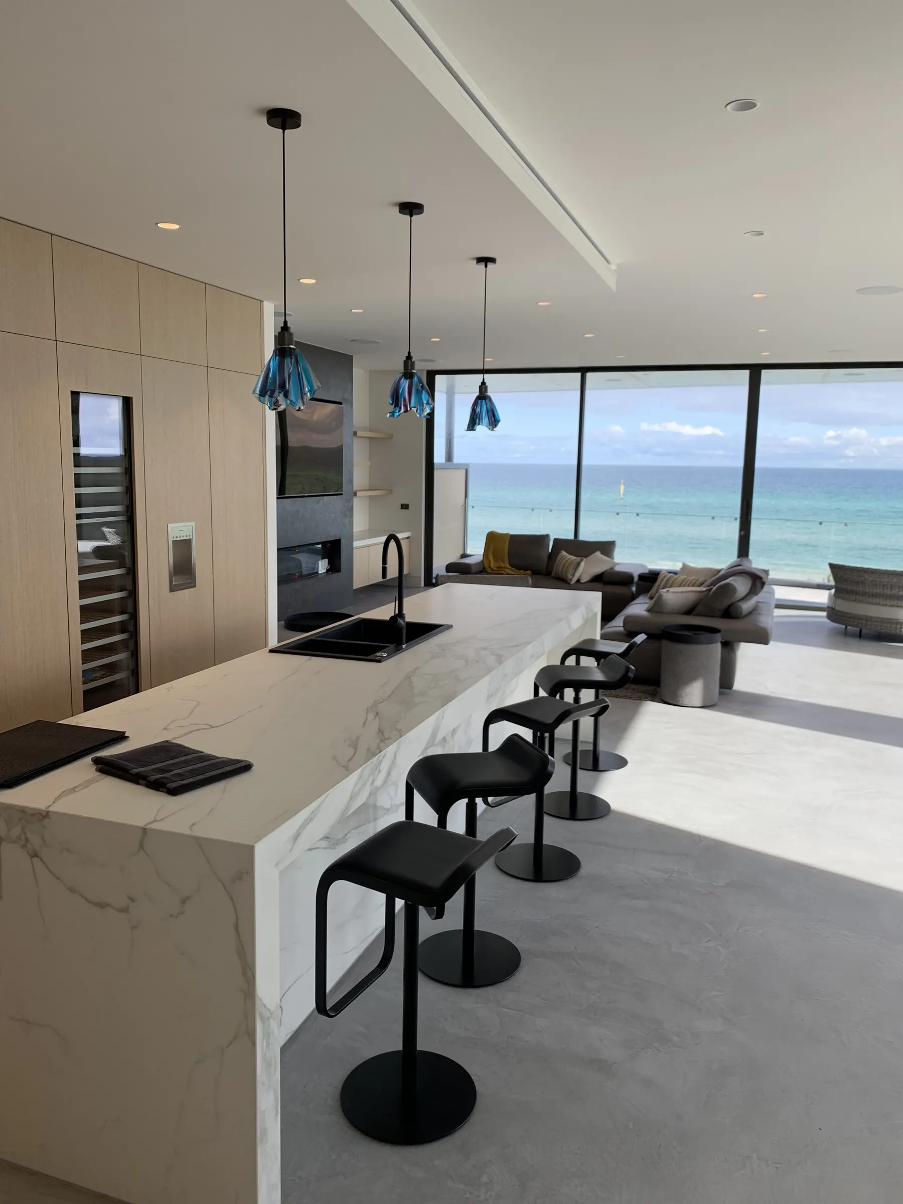 Open-plan kitchen and living looking straight out to the ocean through full-height glazing