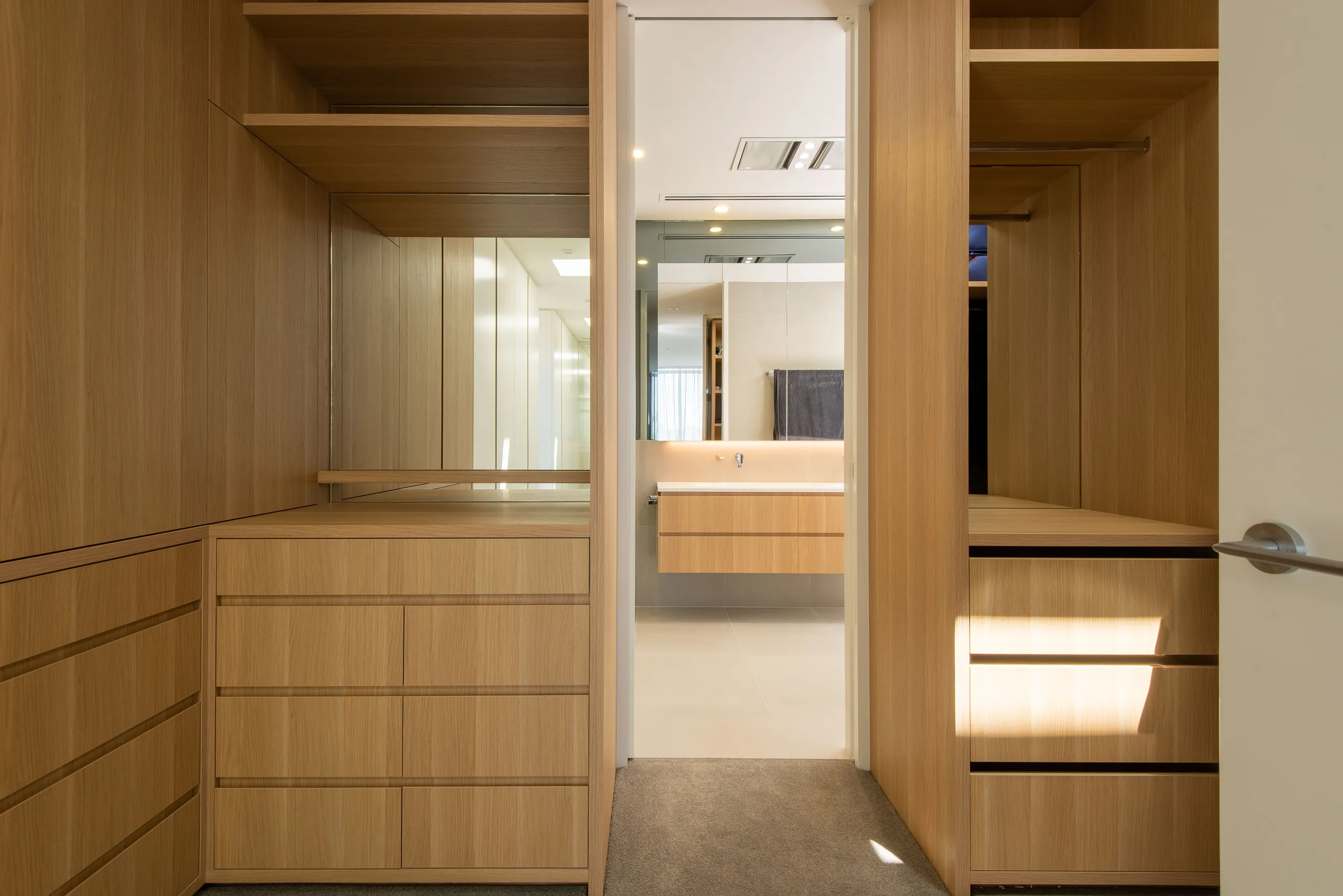 Timber dressing room joinery opening through to the bathroom beyond
