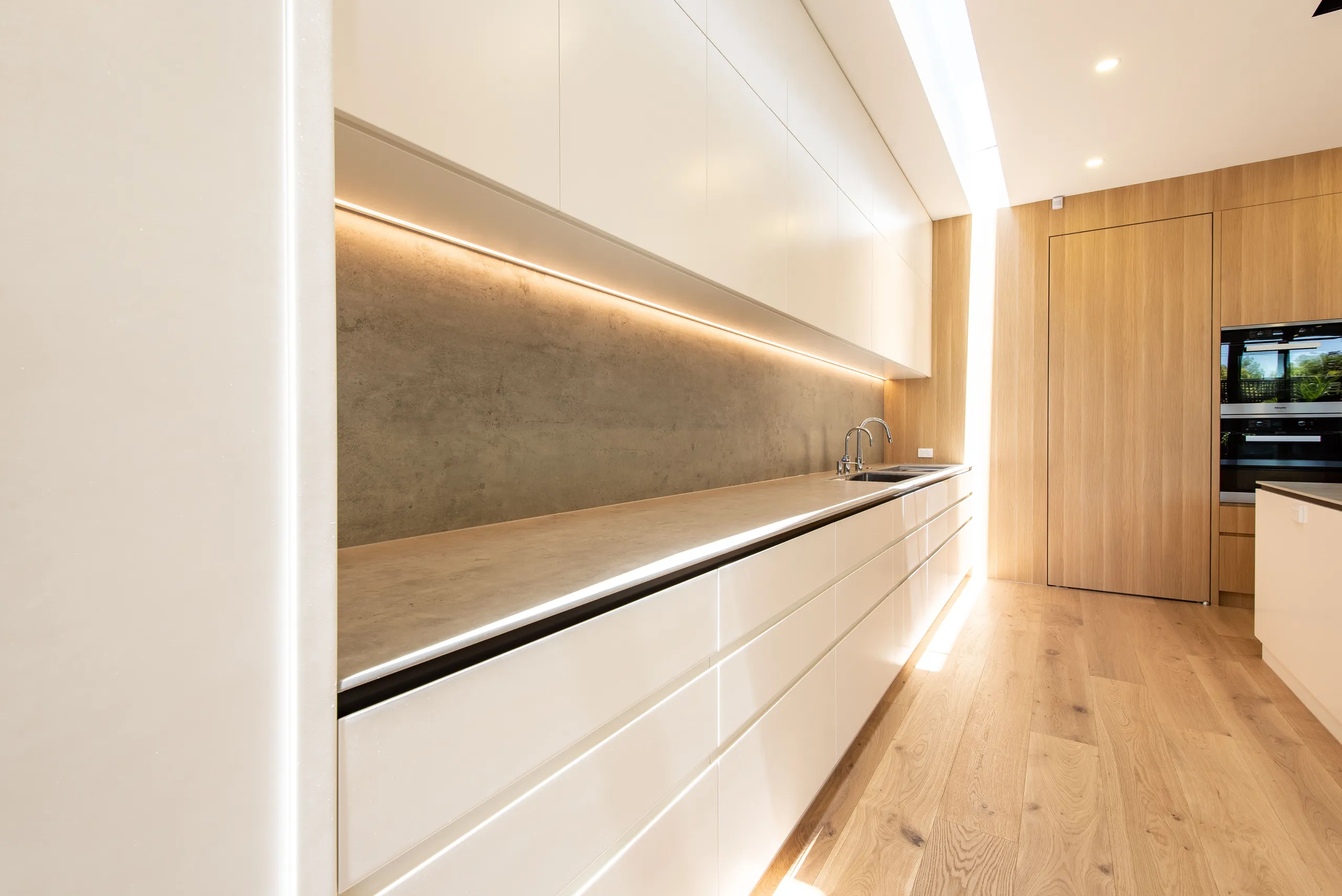 Detail of a lit joinery recess running the length of the kitchen
