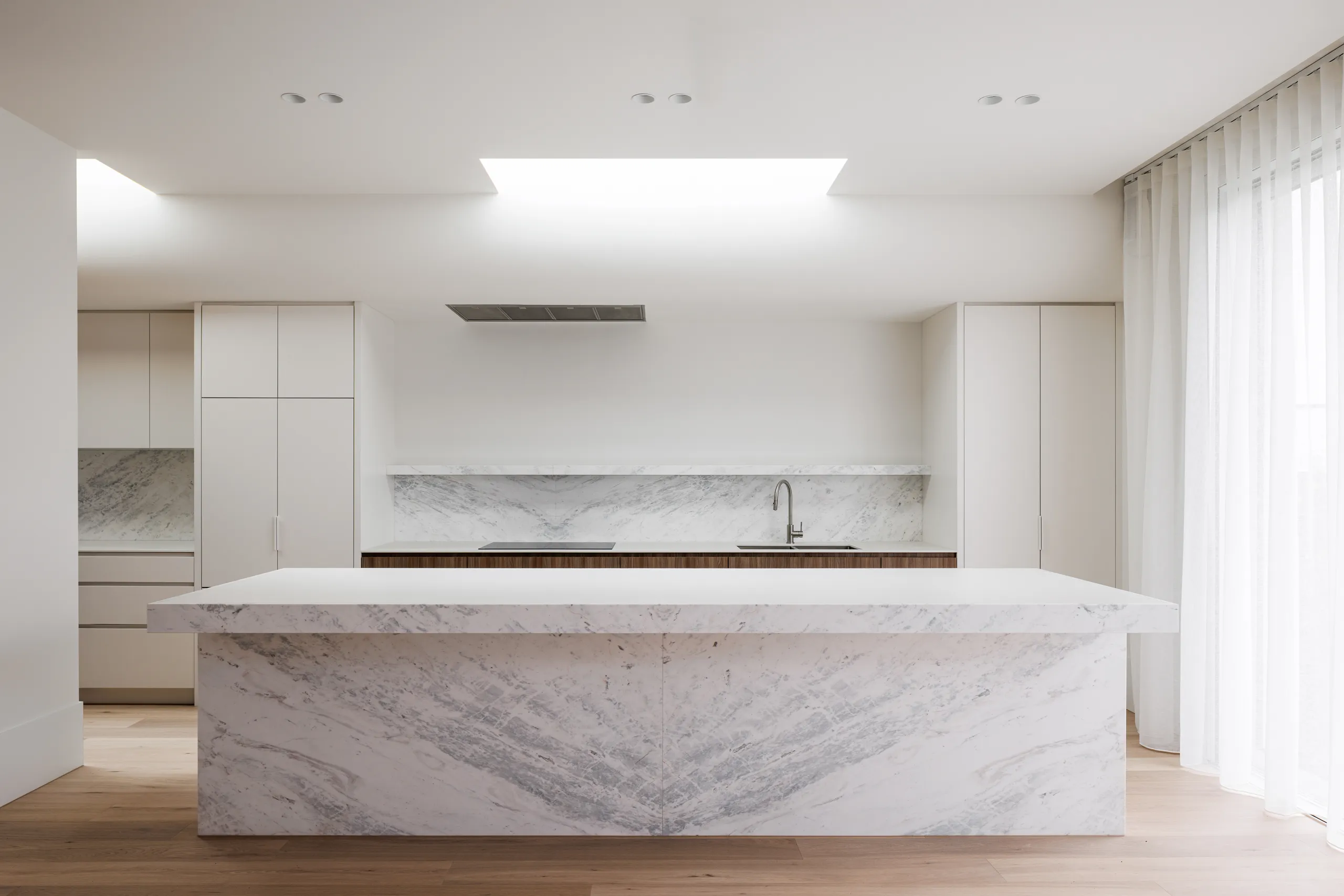 Marble island bench beneath a skylight in the new kitchen