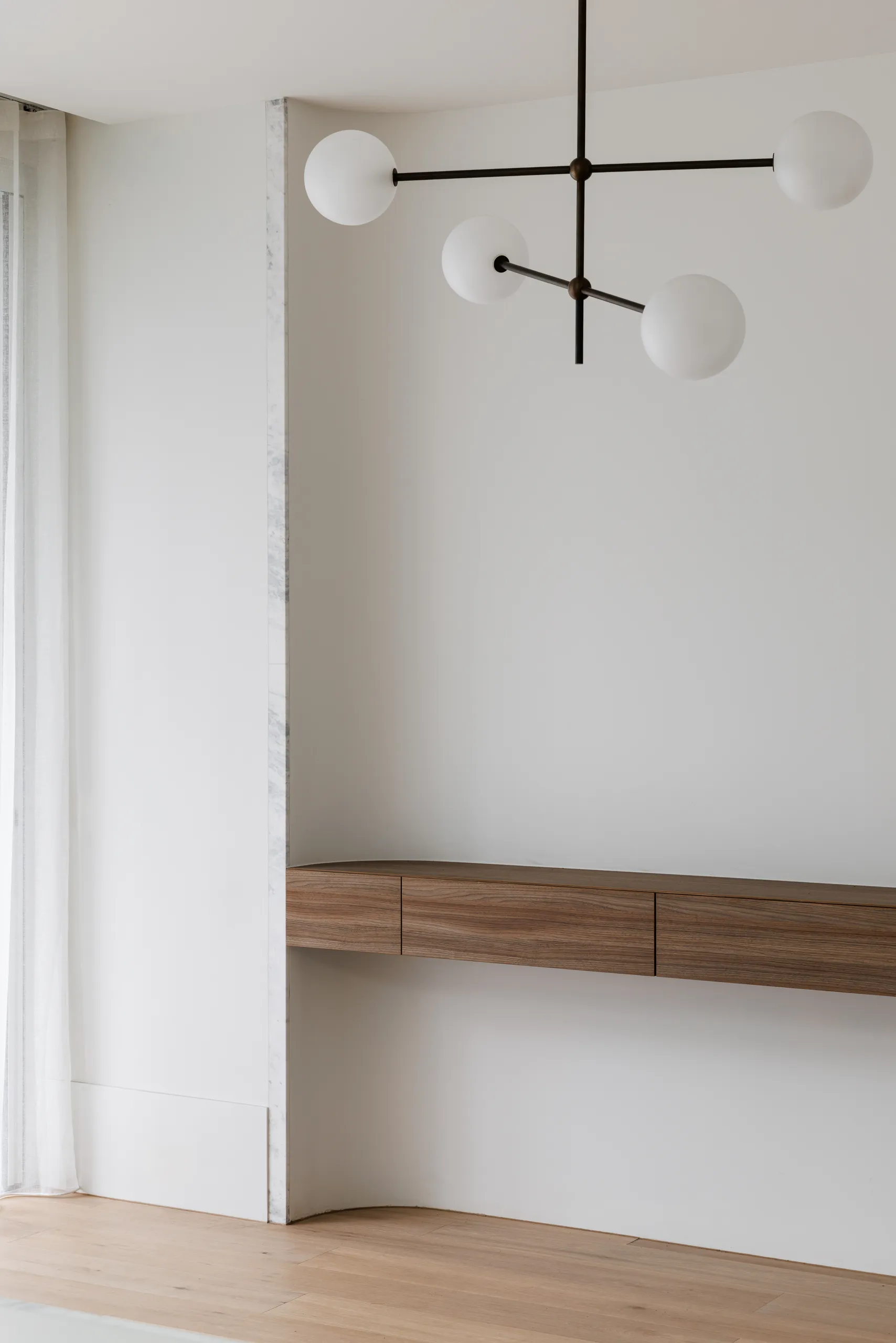 Living space with built-in timber joinery and sculptural pendant
