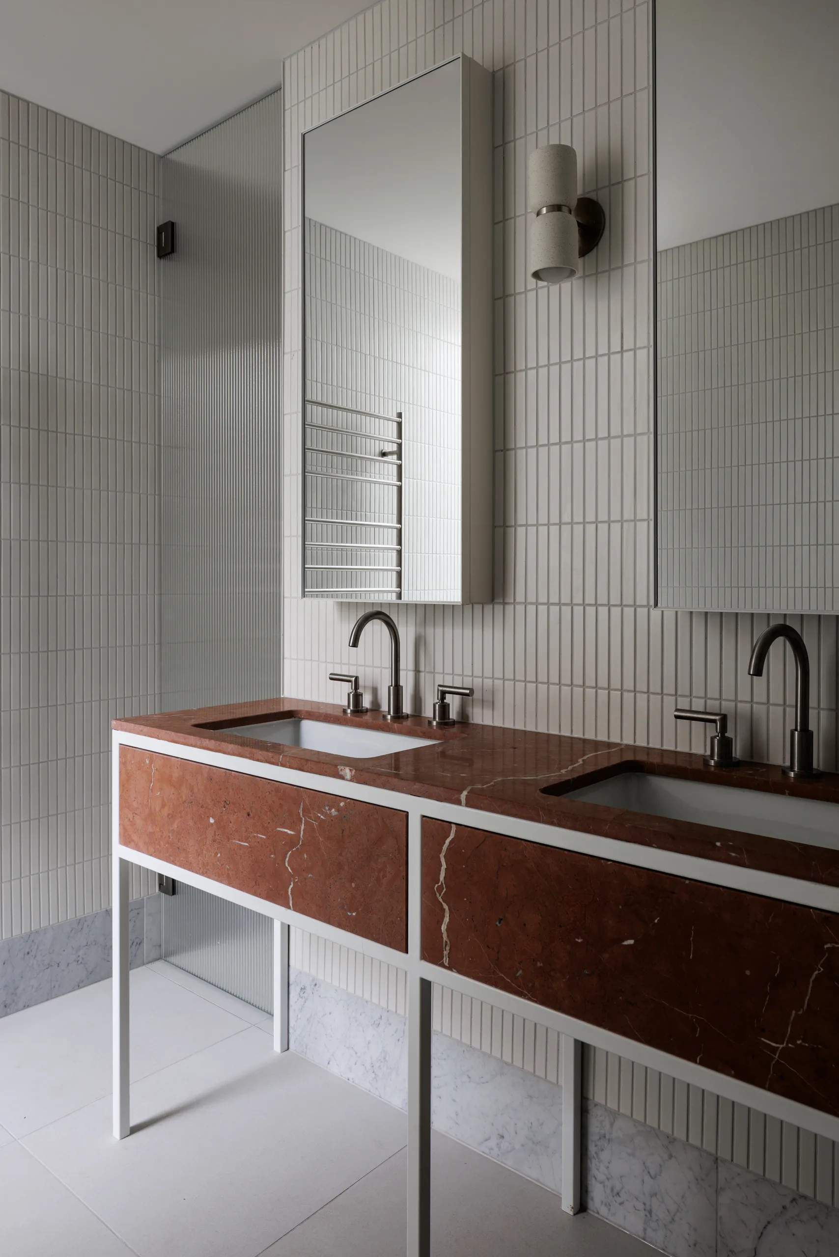 Double vanity in deep red stone against fluted tile