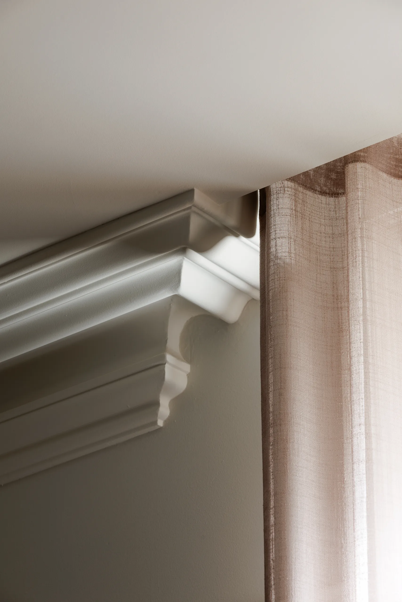 Detail of restored cornice moulding beside a full-height curtain