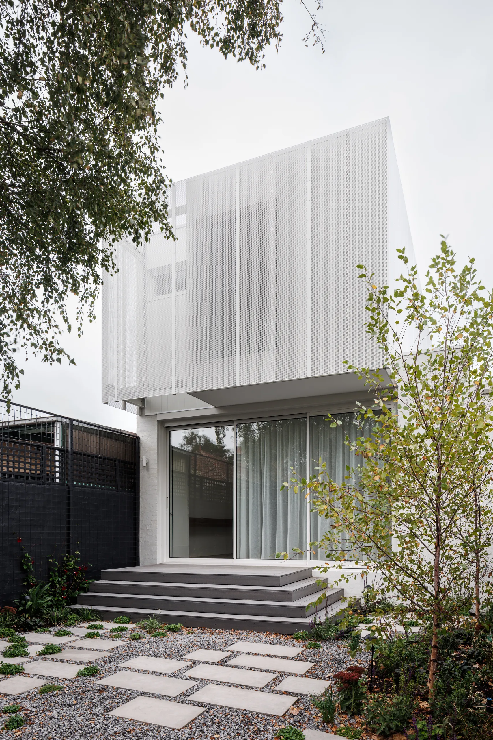 Contemporary rear addition in white perforated screening, seen from the garden